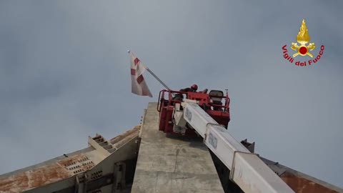 I vigili del fuoco posizionano la bandiera di Genova su Ponte Morandi