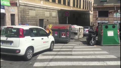 Si stacca il freno a mano, auto travolge i cassonetti e sfiora un bus